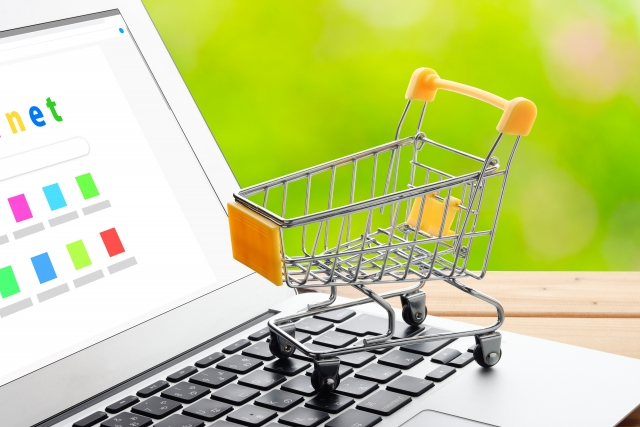 A small shopping cart sits on the keyboard of an open laptop.