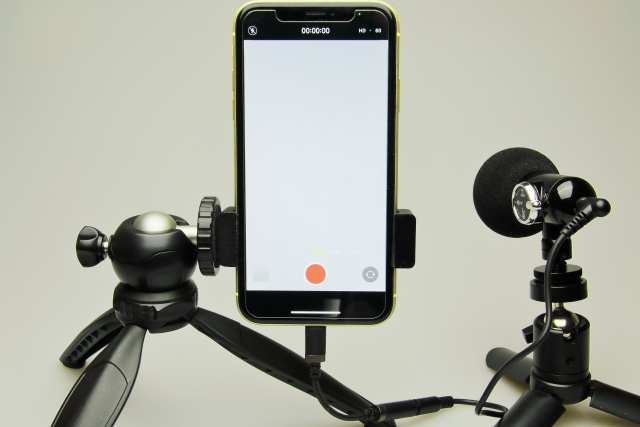 An iPhone set on a tripod with the screen set to record a video.