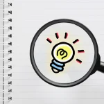 A magnifying glass magnifying a drawing of an illuminated light bulb.